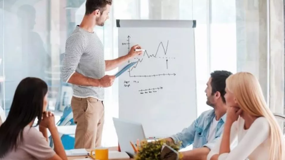 Gruppe von Fachleuten bei einer Besprechung, die gemeinsam an einem Flipchart eine taktische Planung für den Vertrieb ausarbeiten, um praxisnahe Unterstützung für das Tagesgeschäft zu bieten.
