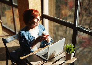Eine Frau sitzt entspannt in einem Café und genießt ihren Kaffee – ein Moment der Ruhe und Gelassenheit im Alltag.