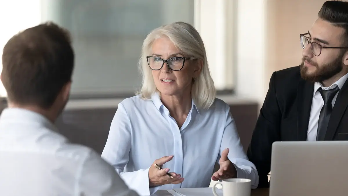 Einwandbehandlung im Verkauf Drei Personen im strukturierten Verkaufsgespräch mit Fokus auf Kundenargumente