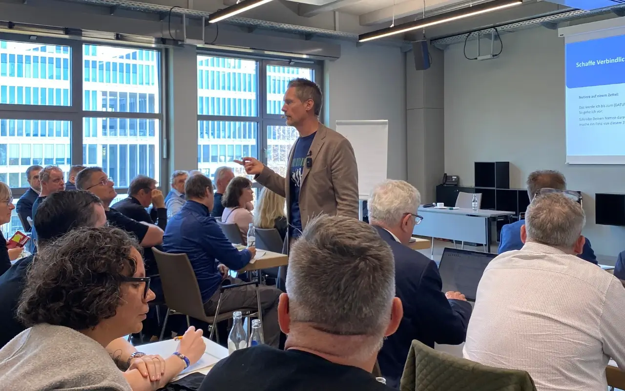 Dirk Stöcker spricht mitten im Publikum über Fokus und Zielklarheit, während die Zuhörer aufmerksam folgen.