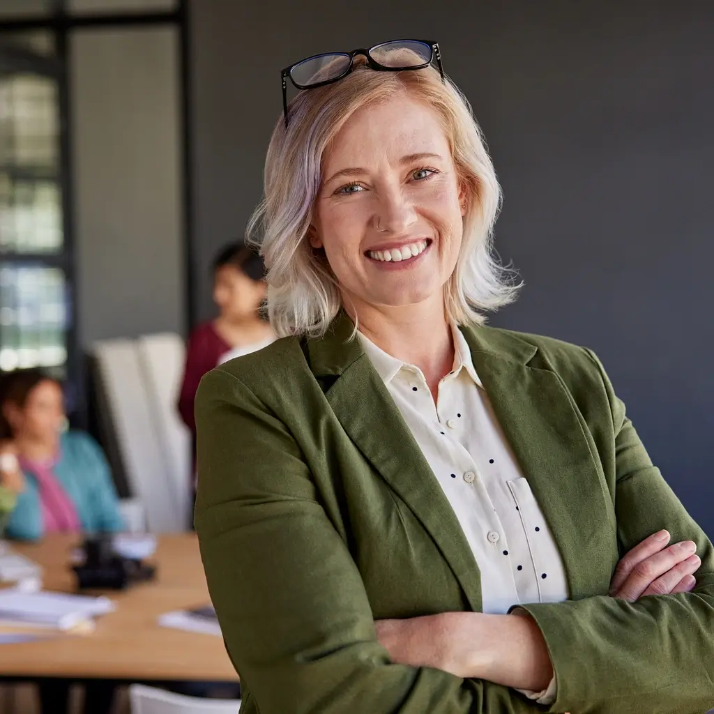 Souveräne Geschäftsführerin blickt freundlich in die Kamera, mit zwei weiteren Führungskräften im Hintergrund, symbolisiert strategische Führung und Teamstärke mit triup®.