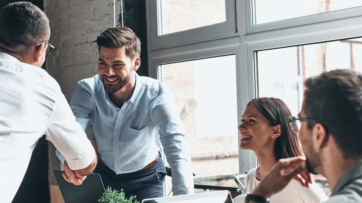 Verkaufstraining Vier Personen im Kundengespräch Handschlag als Zeichen von Vertrauen