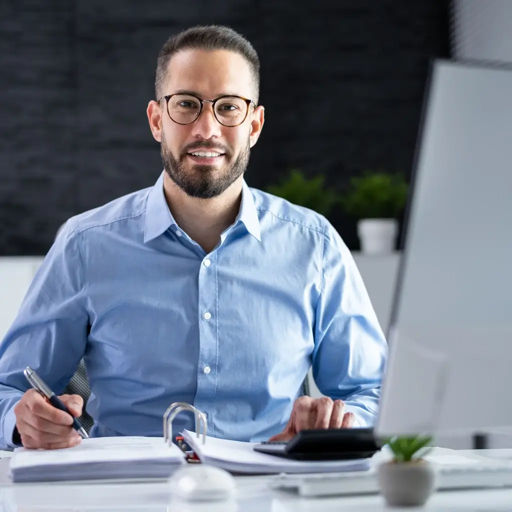 Ein freundlich lächelnder Vertriebsexperte am Laptop, der Souveränität und Präsenz in der digitalen Kundenkommunikation ausstrahlt.